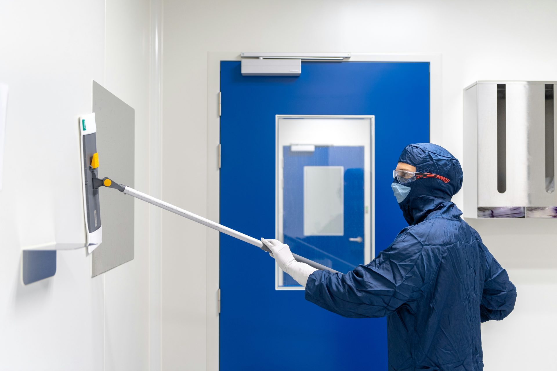 Person cleaning a wall in protective gear