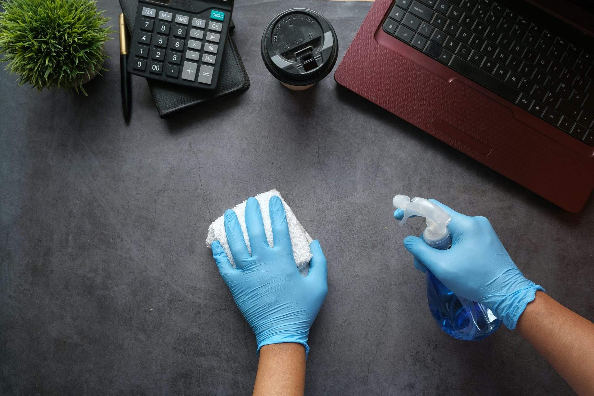 Hands cleaning a desk with spray bottle