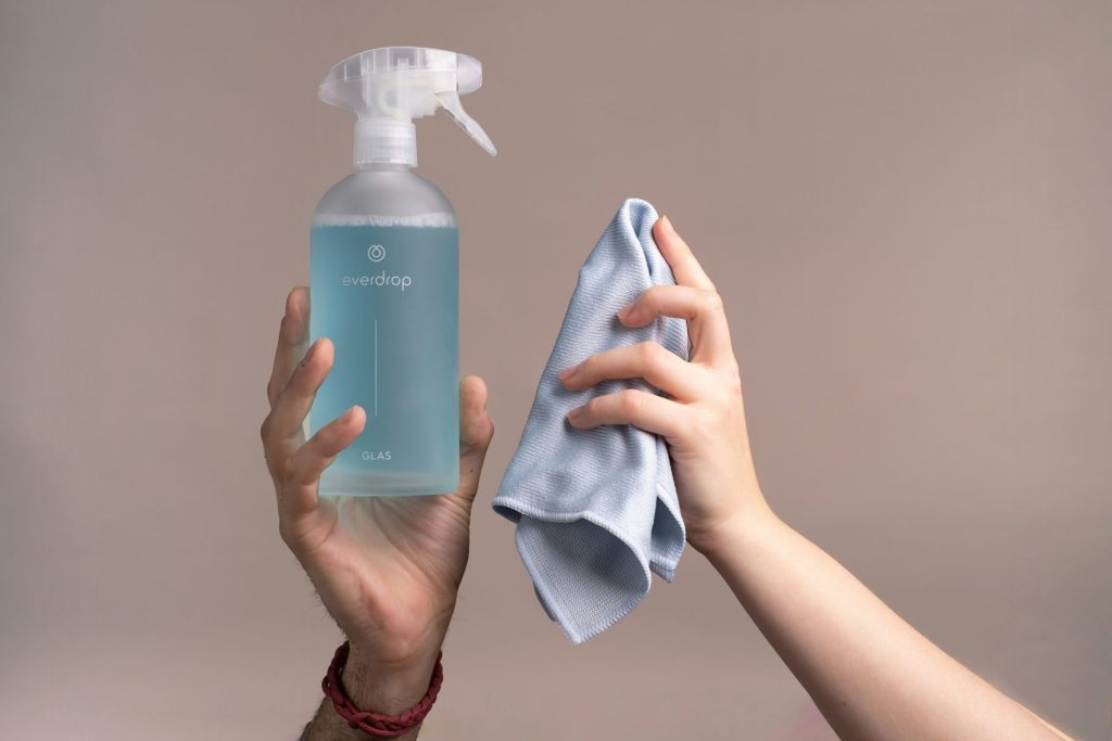 Hands holding cleaning spray and cloth