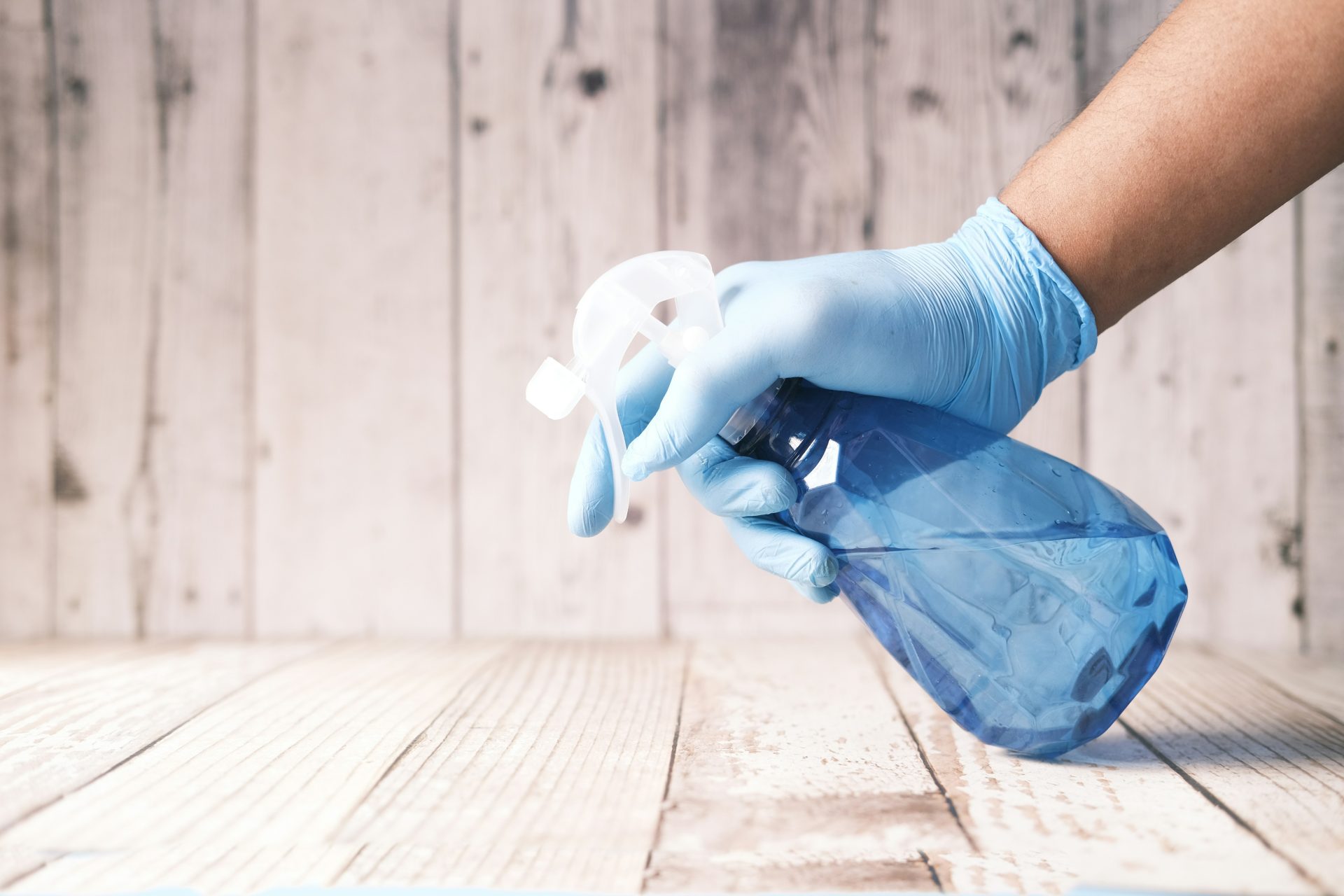 Hand spraying cleaner on wooden surface