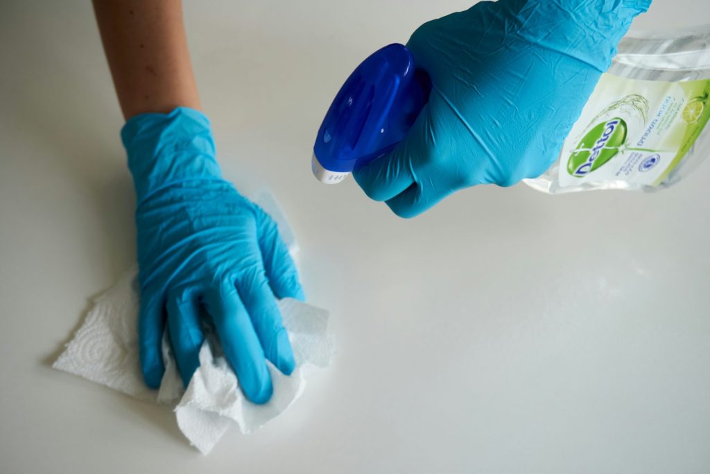 Person cleaning surface with disinfectant spray